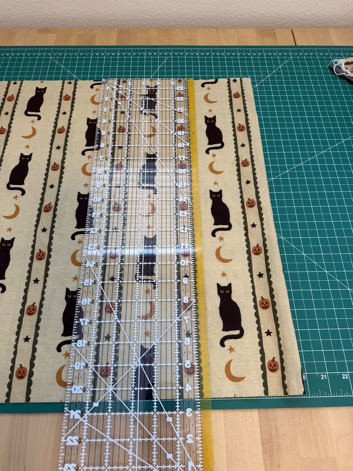 Cutting the cat print with an acrylic ruler on a green cutting mat